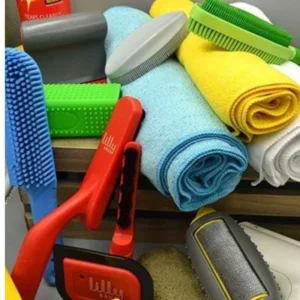 Rubber pet hair remover tool and reusable lint roller placed beside a fabric couch cushion.